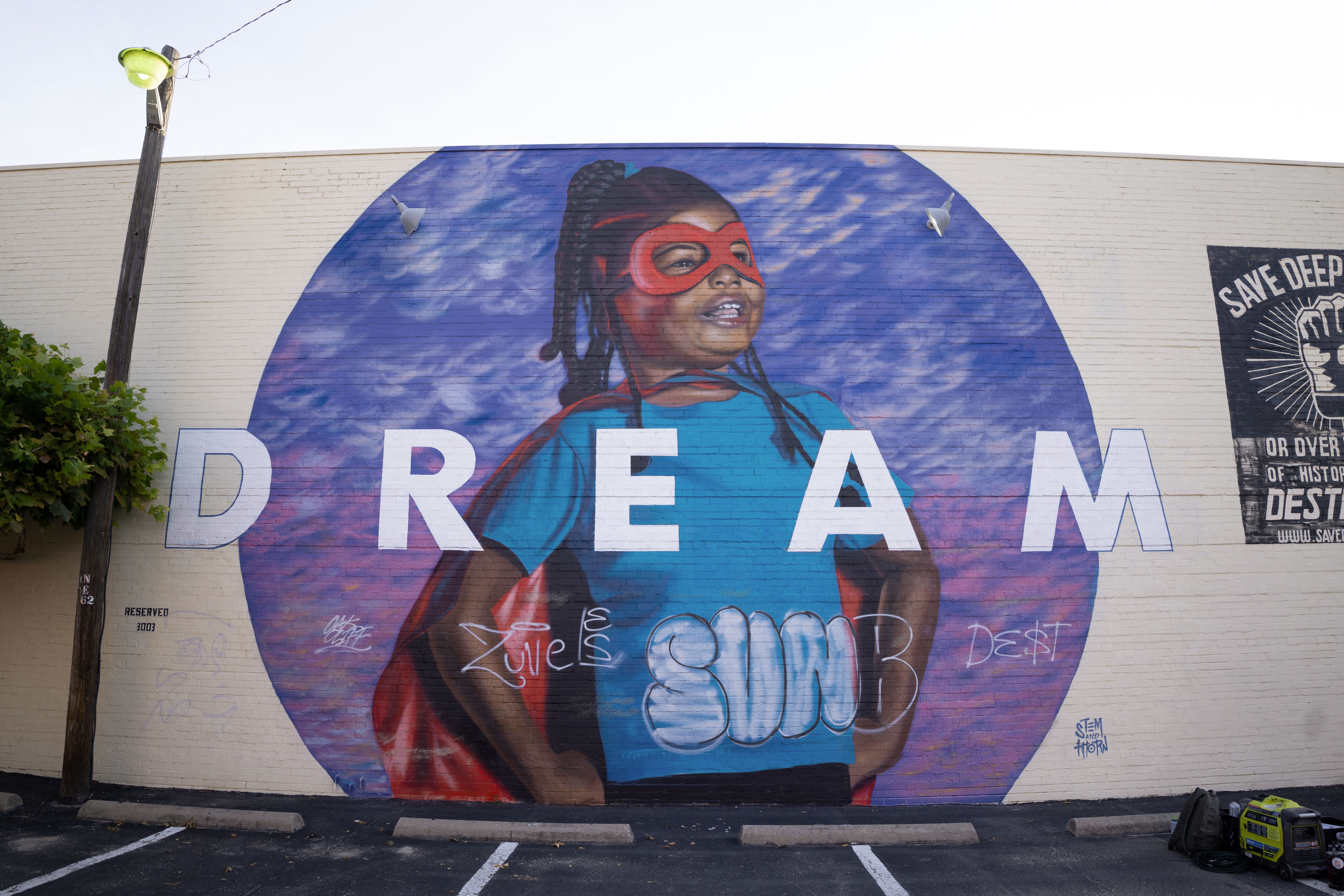 A photo of the "DREAM" mural before it was mended. There is graffiti across the bottom half of the mural, detracting from the imagery and message.