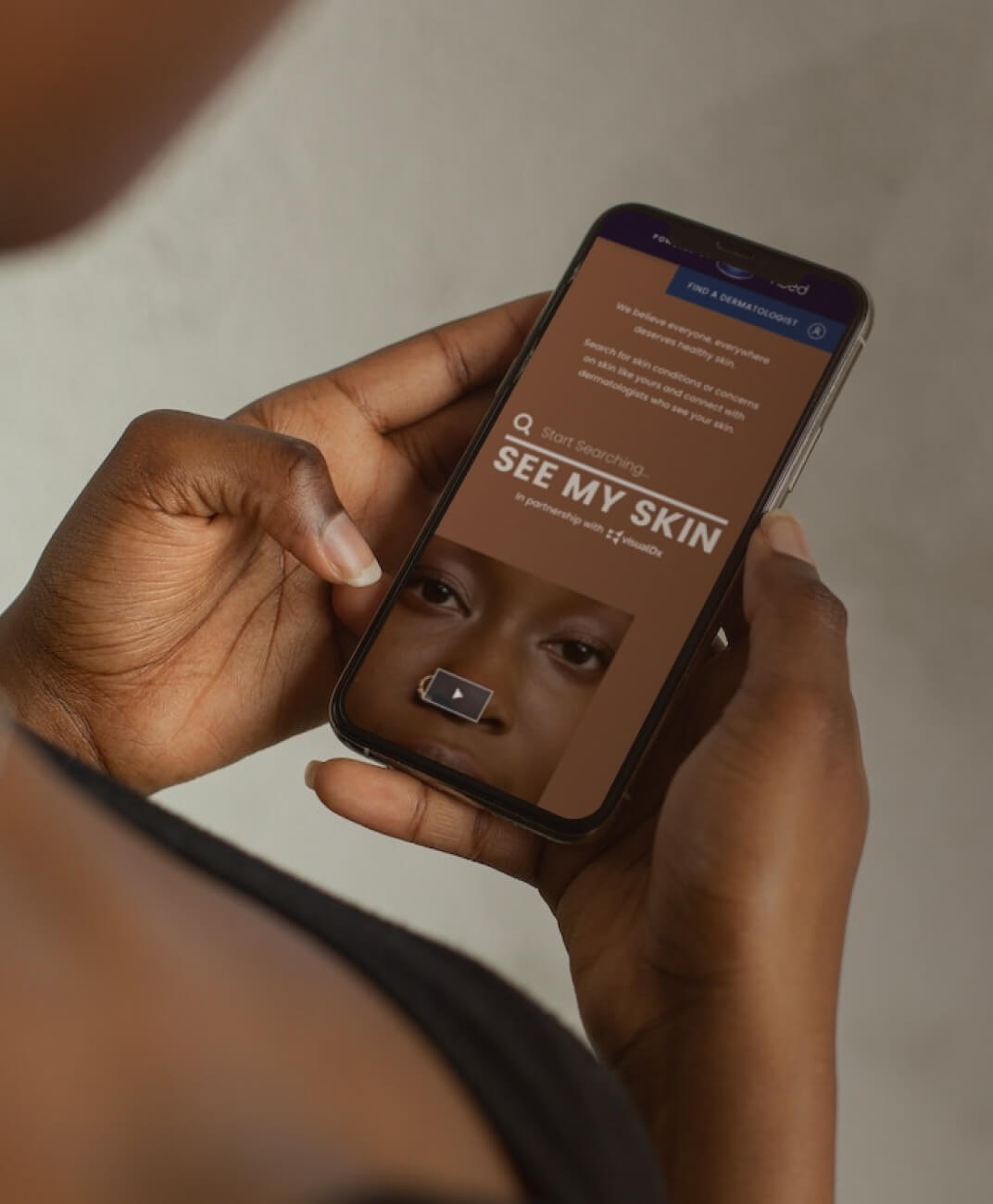 A dark-skinned woman visiting SeeMySkin.com on her phone.