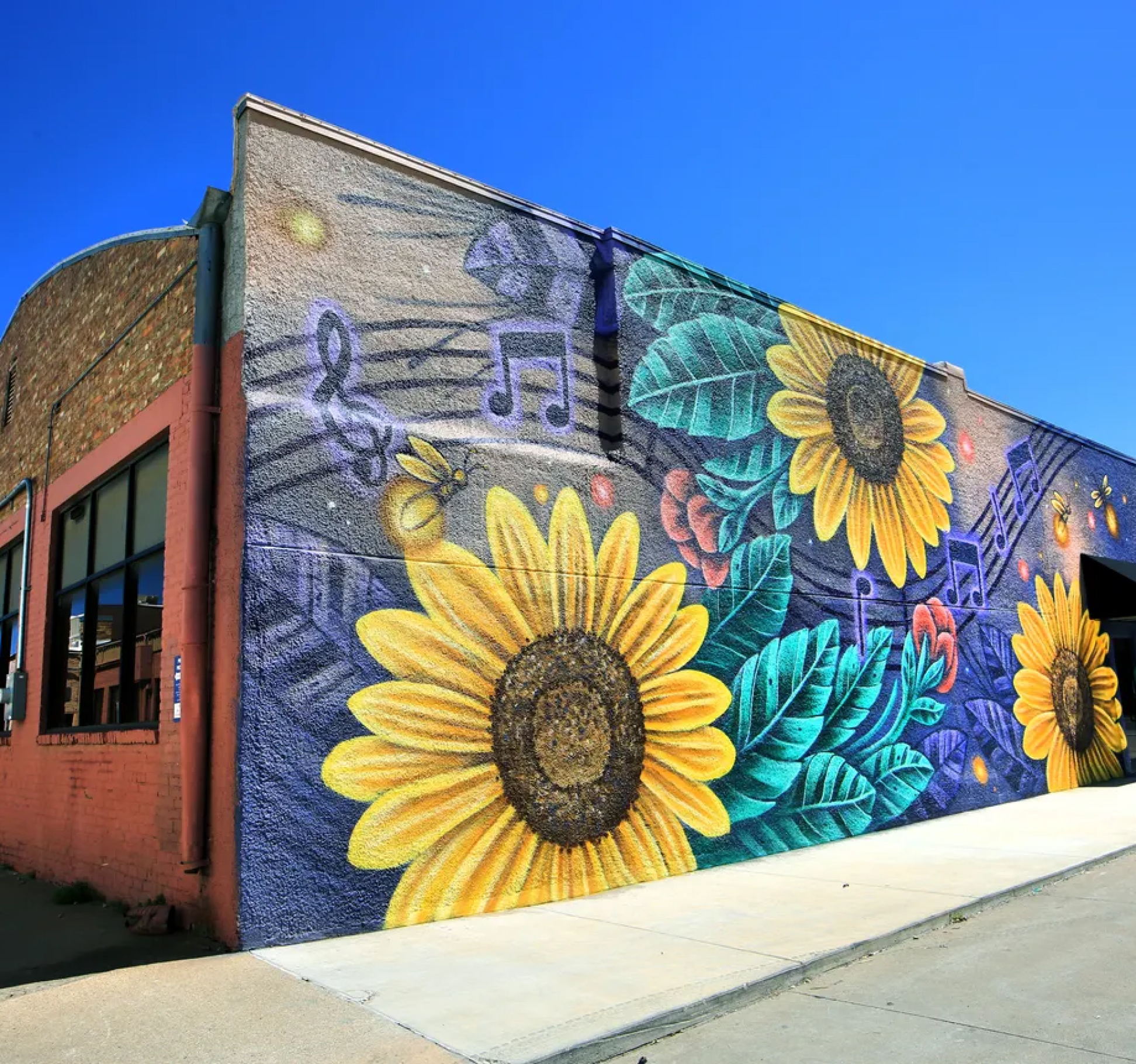A colorful mural of sunflowers overlaid on a dark blue-violet background with musical notes.