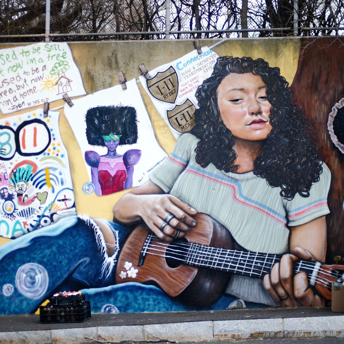 Part of the mural "Star Gazing." A woman with long curly hair is playing a ukulele in this section.